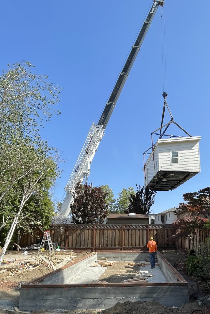 ADU being lifted by crane into backyard.